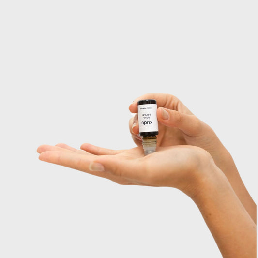 A hand holding Kudu Cosmetica Soul Safari rollon Perfume oil , showcasing a sleek, minimalist design.