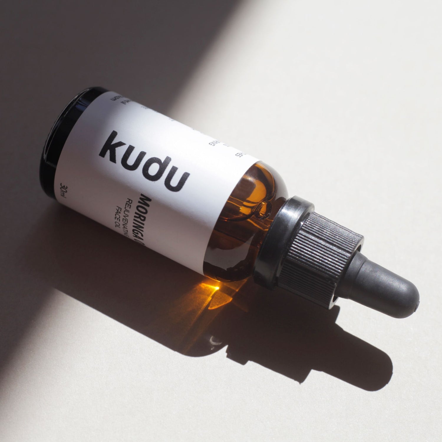 A black and silver flashlight next to a dropper bottle labeled "Moringa Face oil, Kudu."