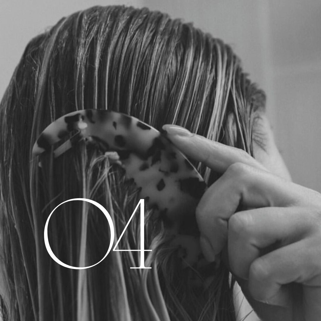 Person holding a spotted hair clip in wet hair, with the number "04" visible, black and white photo.