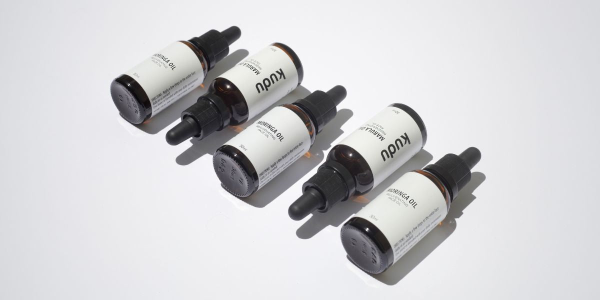 Five dropper bottles with white labels on a light gray background
