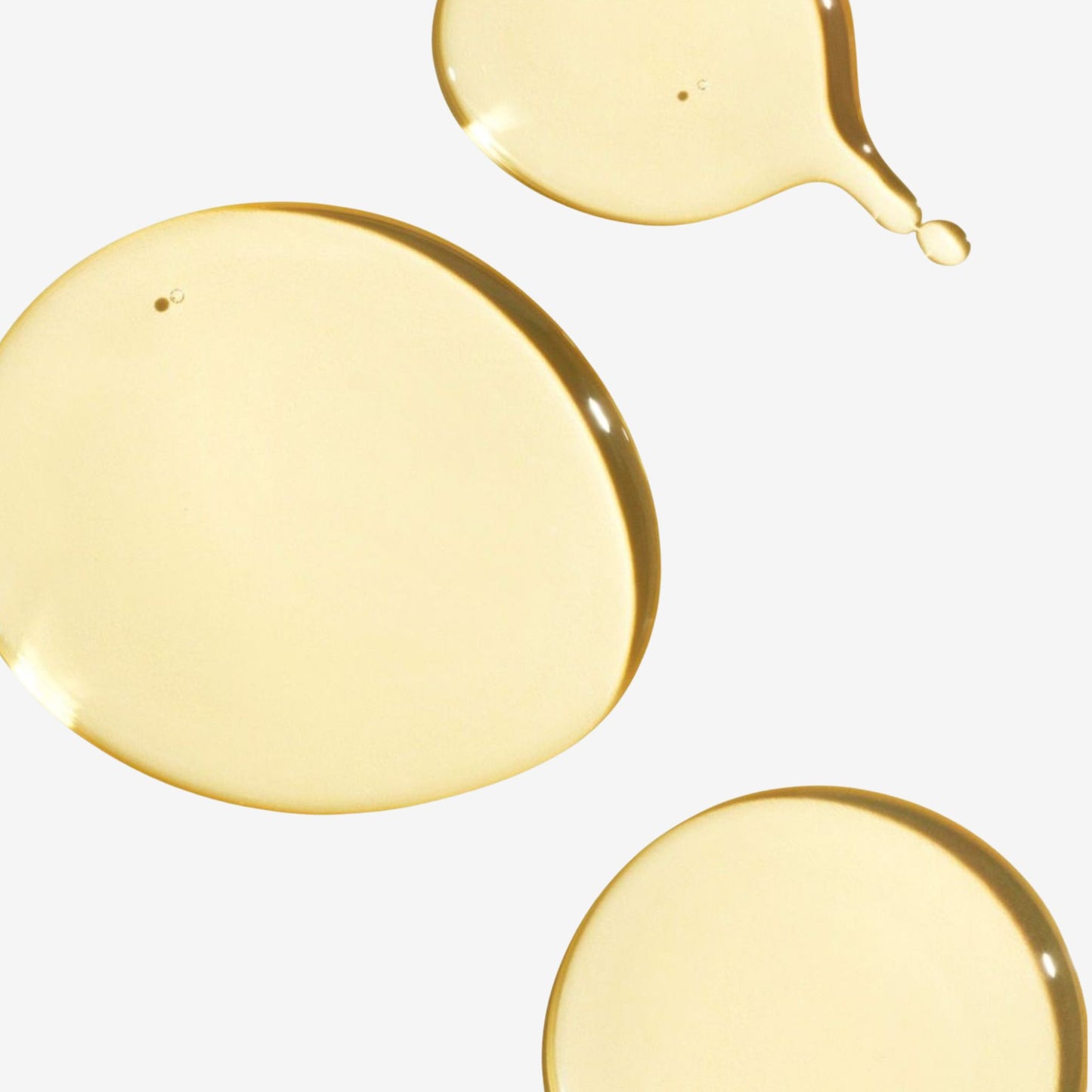 Close-up of yellow liquid droplets on a light gray background