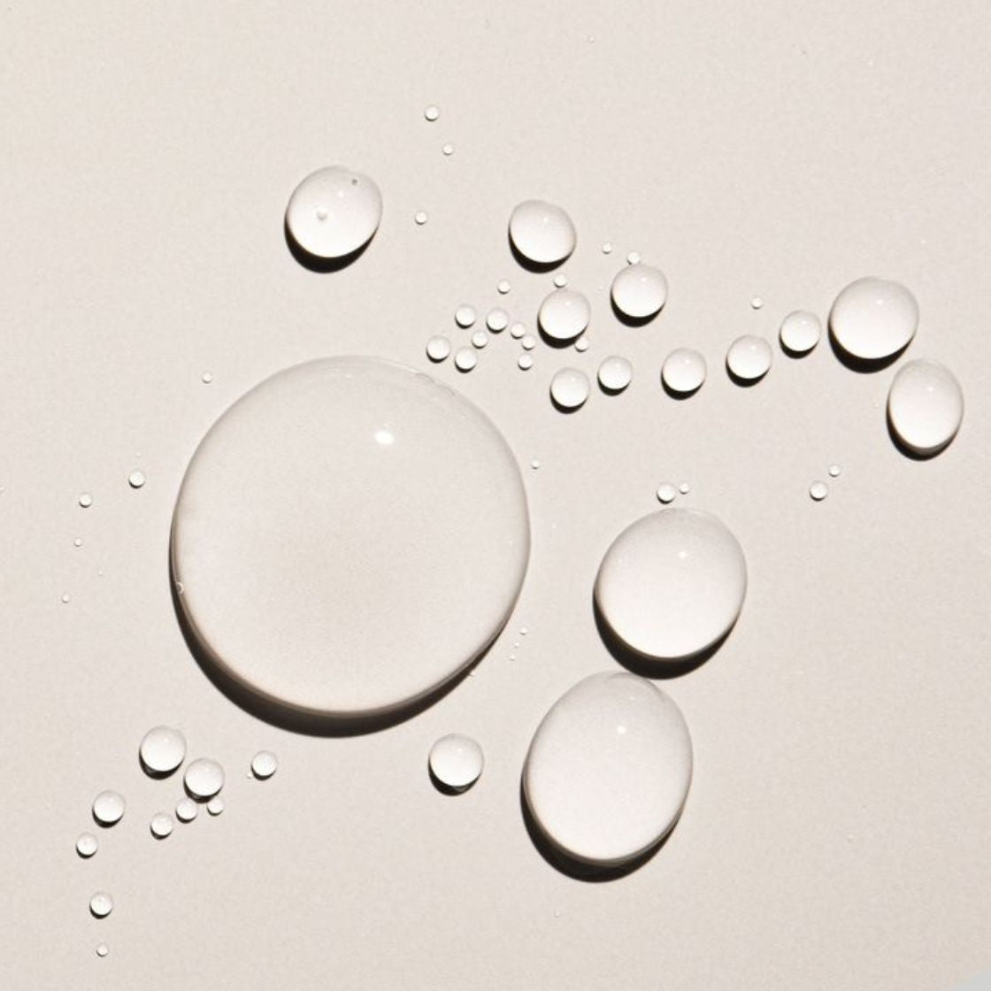 Oil droplets on a beige surface representing Kudu Squalane facial oil