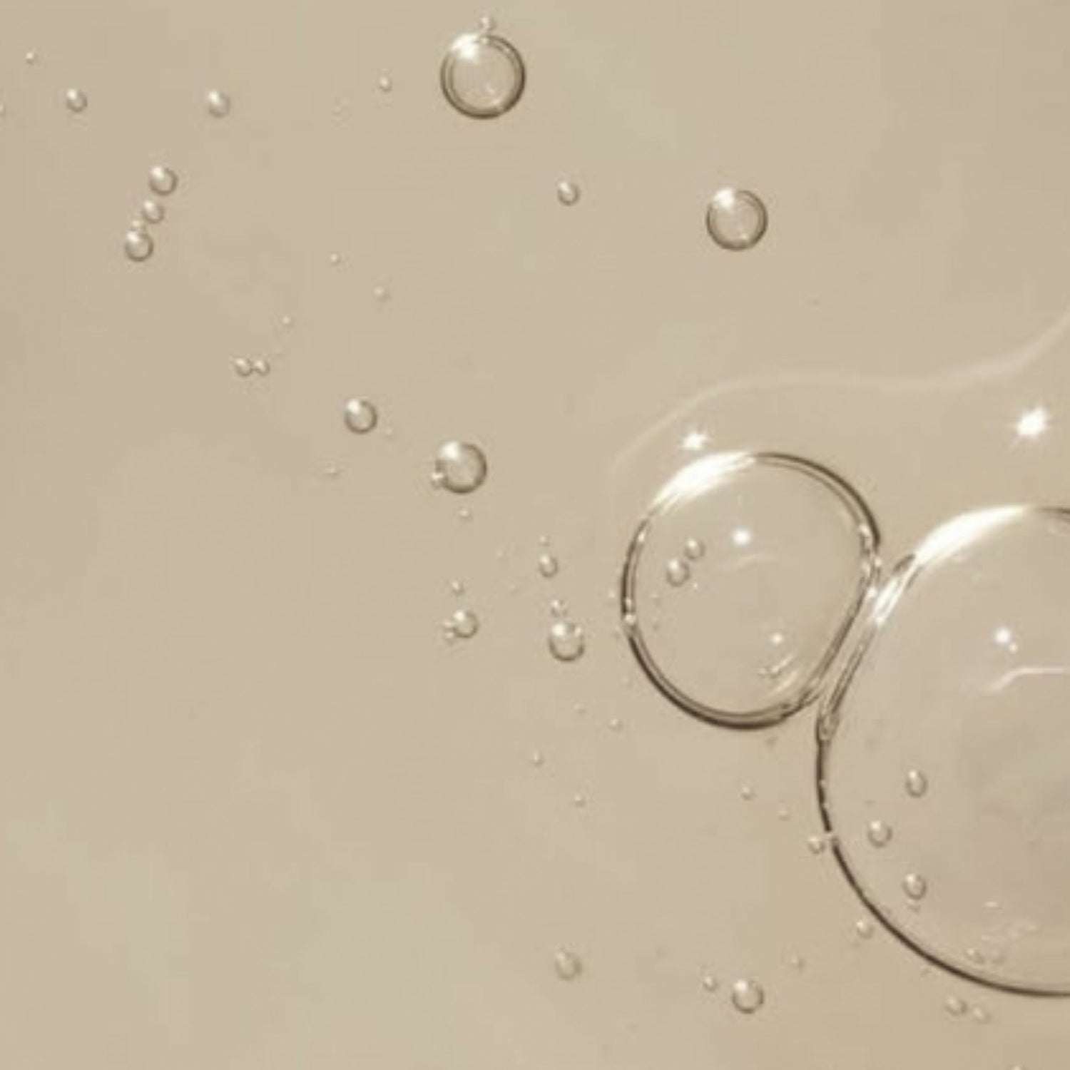 close up of droplets of baobab oil on a beige surface