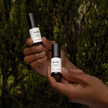 Soul Safari and Desert Moon botanical perfume oils held in hands against natural greenery backround