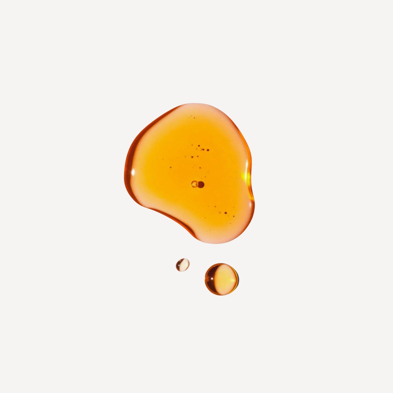 Golden facial oil droplet on a light beige background