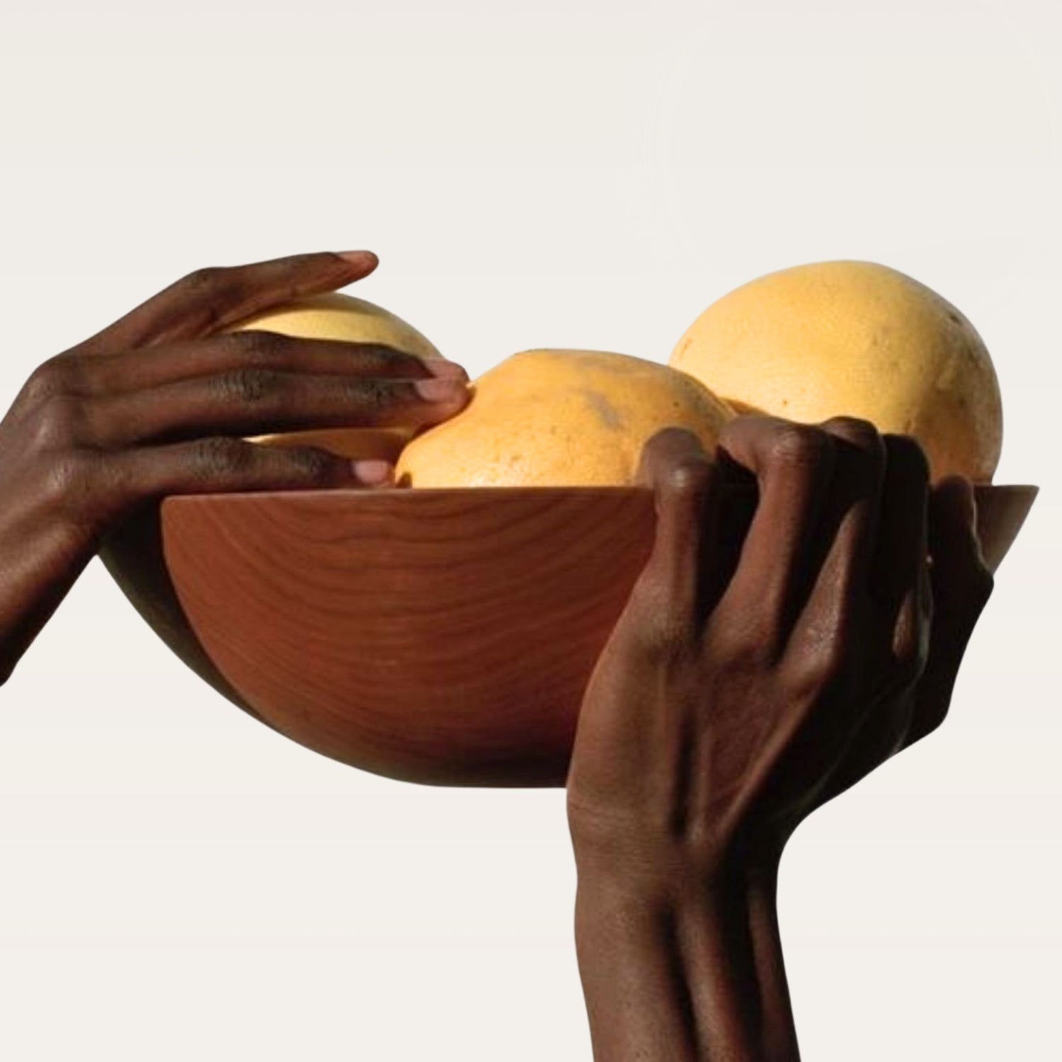 Hands holding marula fruit in wooden bowl, natural skincare ingredient