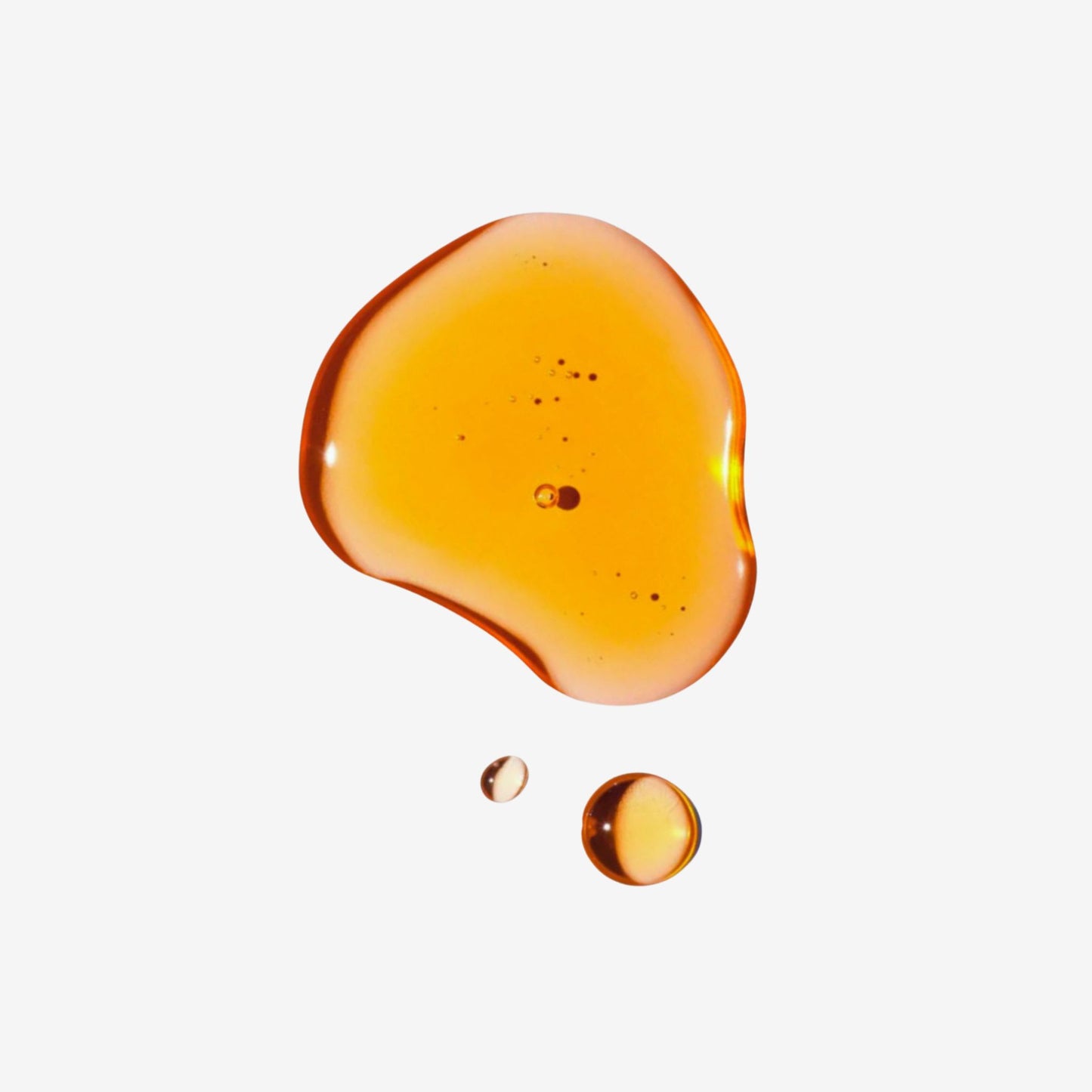 Amber-colored liquid droplet on a white background
